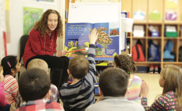 An engaged teacher reading out loud to the class from a big Shared Reading book.